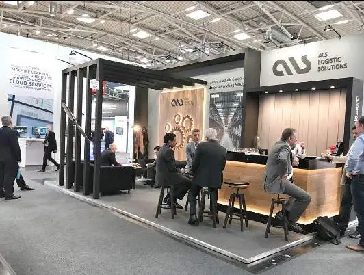 Visitors at the ALS stand bar with a gear-motif wall at Inter Airport Europe 2017 in Munich