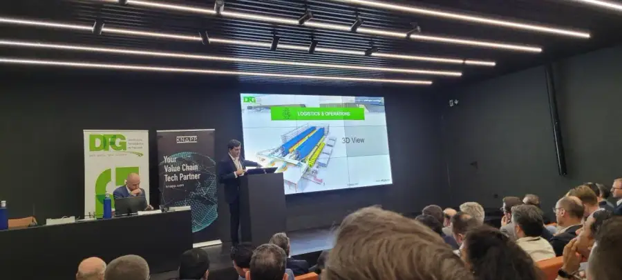 Speaker presenting a 3D warehouse layout at Move Healthcare 2023 in San Sebastián, beside KNAPP and DFG banners