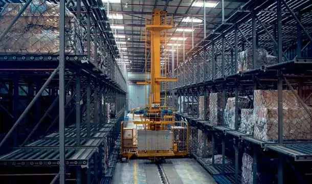 Yellow elevating transfer vehicle between multi-level ULD racks loaded with netted cargo at dnata Freight Gate 8, Dubai