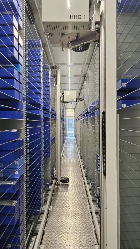 Robotic handling device above shelves of blue medicine boxes in the Al Farsi fully automated pharma store, Muscat, Oman